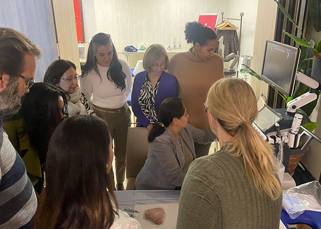 La doctora Marjorie Garcerant en una práctica del curso Ecografía en Medicina Estética, explicando con un ecógrafo rodeada de asistentes que la observan atentamente